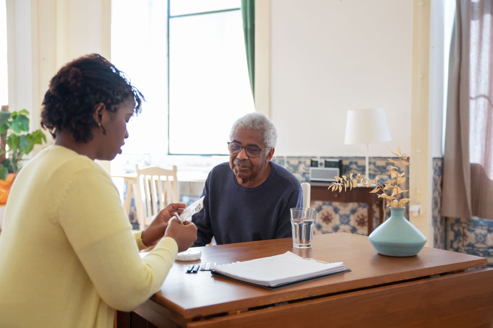 A carer helping with medication at the kitchen table